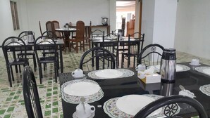A dining area with tables set for four, chairs, and a coffee machine. - Golden Palace Hotel Hpa An (Hpa-An)