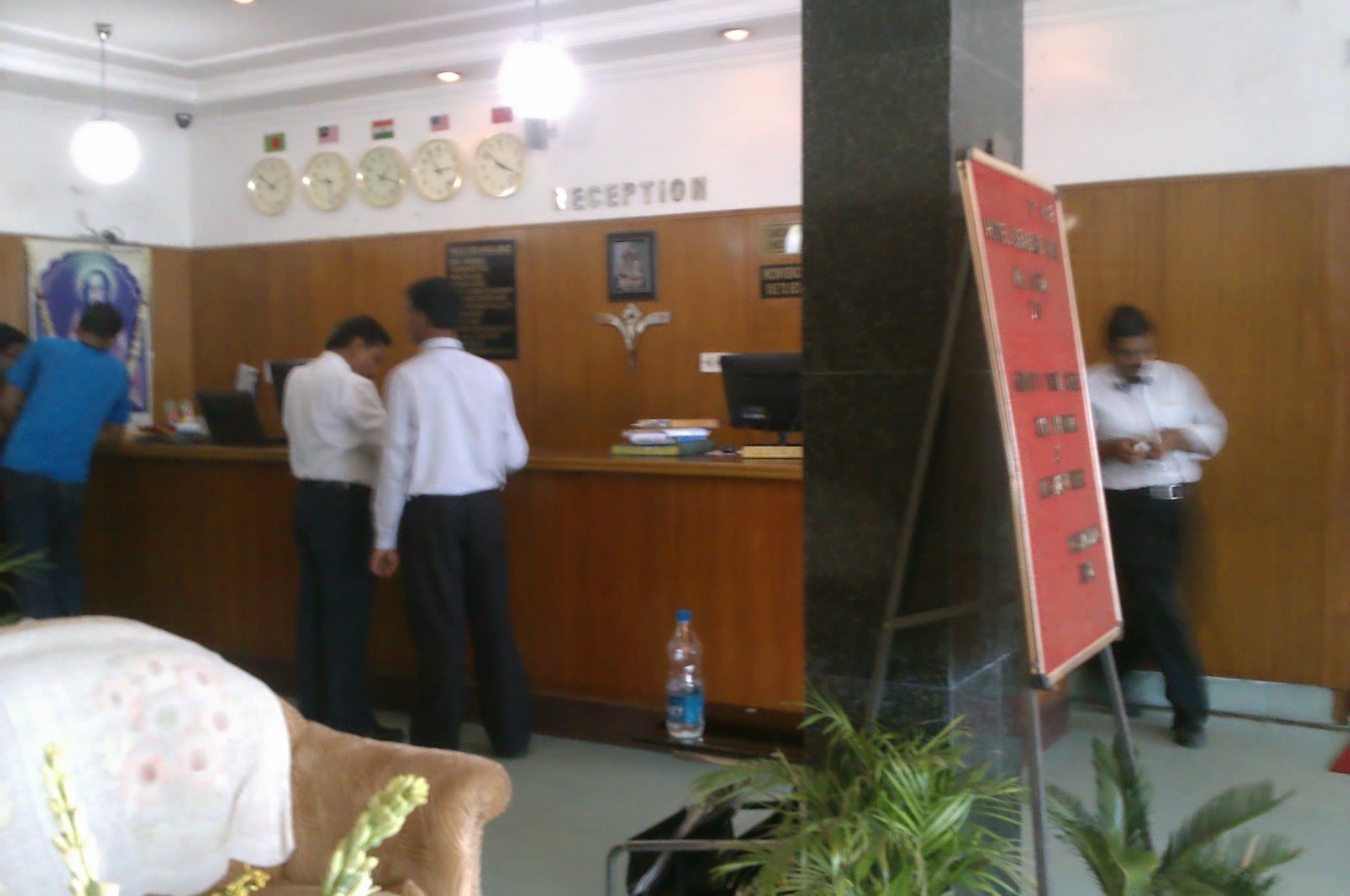 A reception area with a wooden reception desk, a clock, and a signboard.