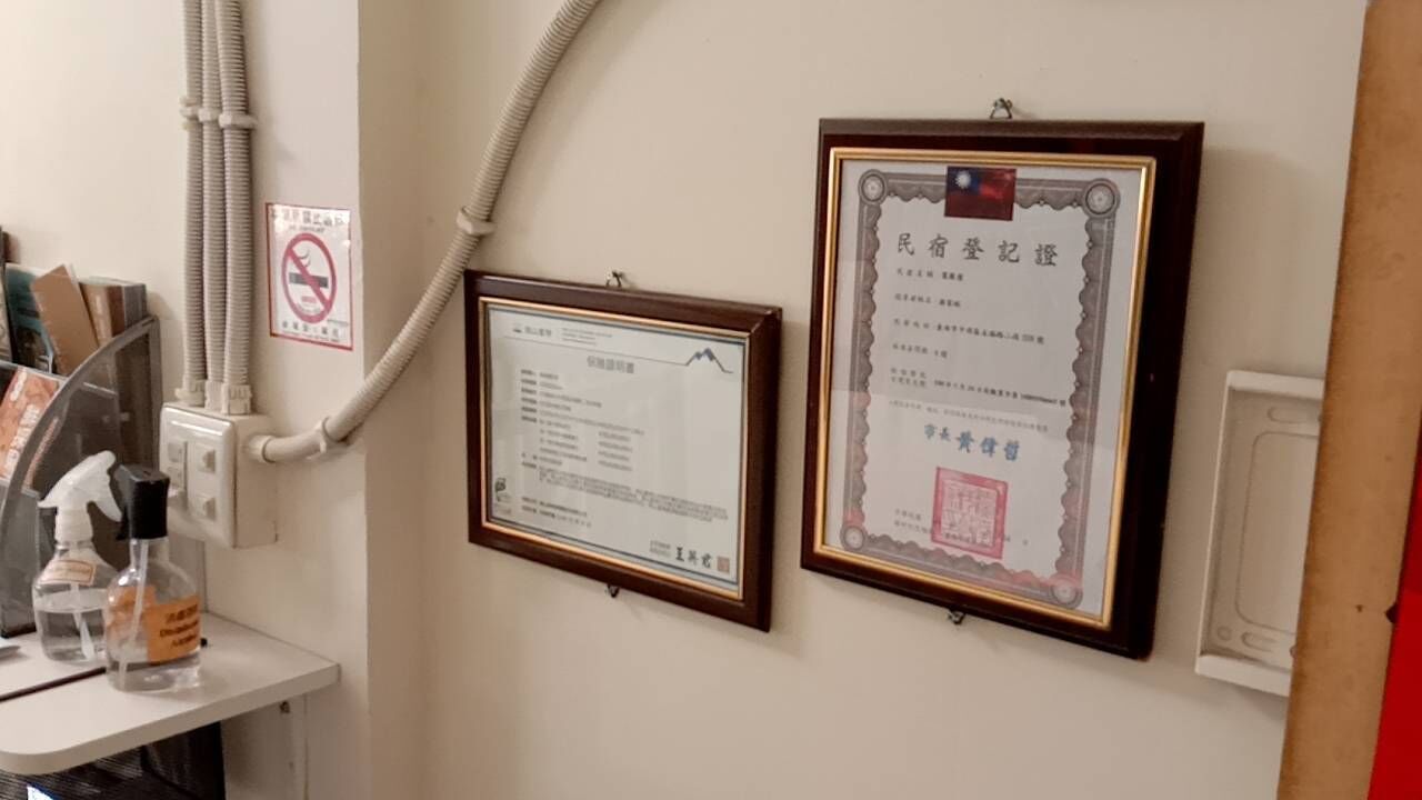 A wall with two framed certificates and a no-smoking sign.