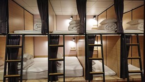 A bunk bed room with wooden walls, black curtains, and a small bedside table with a lamp. - Temple Side - Hostel (Tainan)