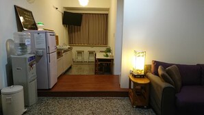A compact living space with a kitchenette, a small dining area, and a seating area with a sofa and a table. - Temple Side - Hostel (Tainan)