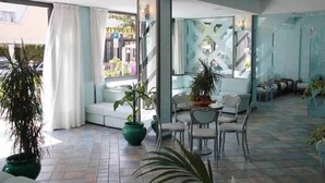 Un hall d’hôtel avec un espace salon, des plantes en pot et une vue sur la rue.