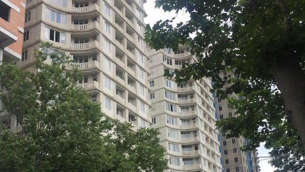 A multi-story residential building with balconies, a parking area, and trees along the street. - Mia B&B Tbilisi (Tbilisi)