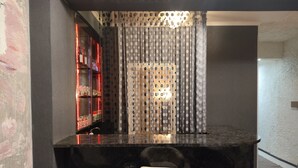 A modern kitchen with a black countertop, a white chair, and a black chair. There is a shelf with red lighting and a curtain with a polka dot pattern. - Mia B&B Tbilisi (Tbilisi)