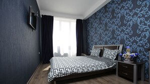 A bedroom with a bed, a nightstand, a TV, and a window with curtains. - Mia B&B Tbilisi (Tbilisi)