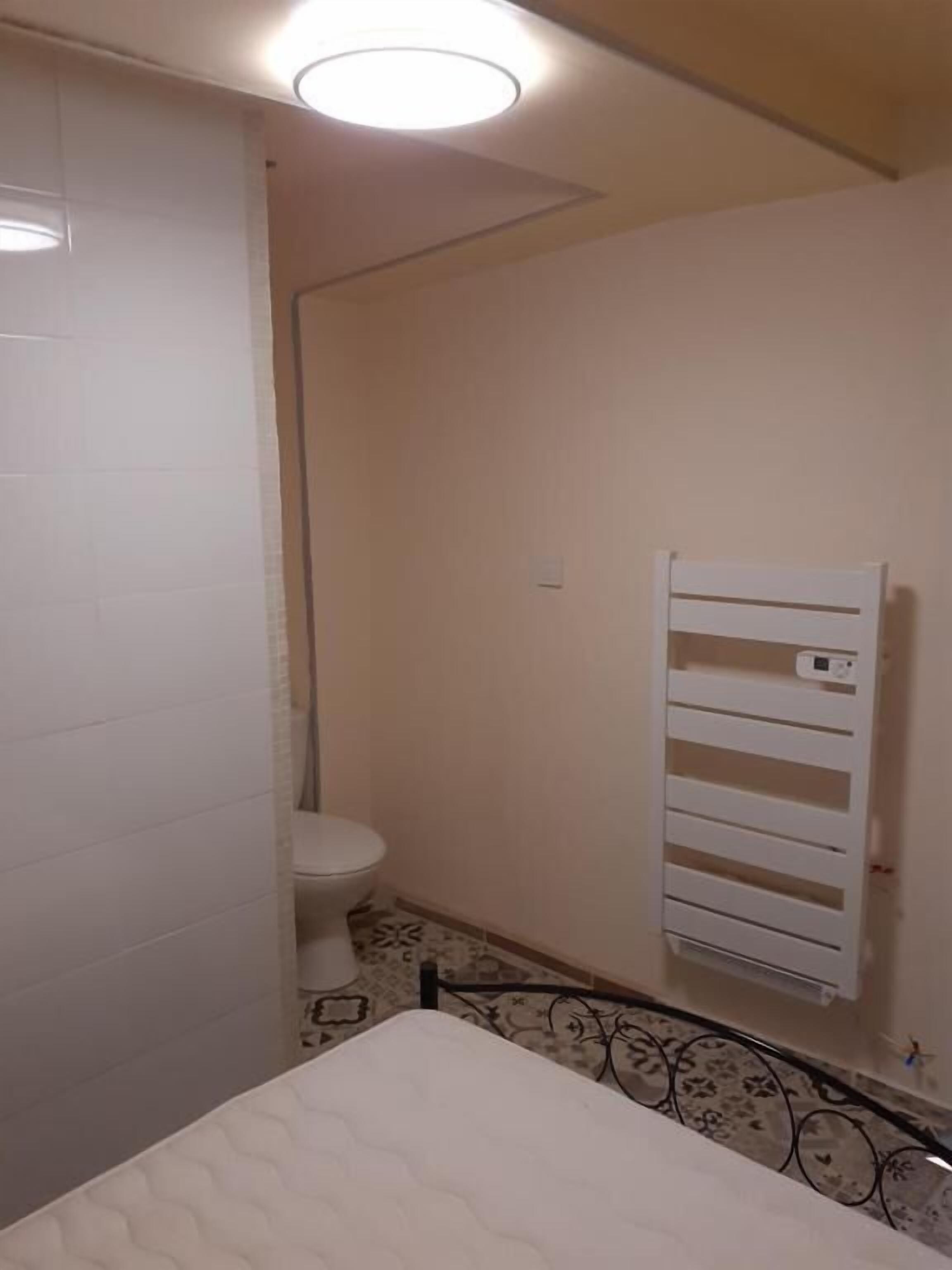 Un baño pequeño y funcional con inodoro, radiador y suelo estampado.