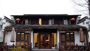 A traditional building with a tiled roof, wooden doors, and a balcony with a railing.