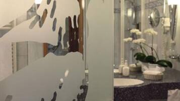 Un baño de diseño moderno, con un espejo grande, un lavabo con encimera oscura y un inodoro.