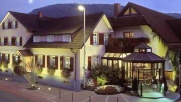 Un hotel de estilo arquitectónico europeo tradicional, con un pabellón central con techo de vidrio y una hilera de habitaciones con ventanas visibles.