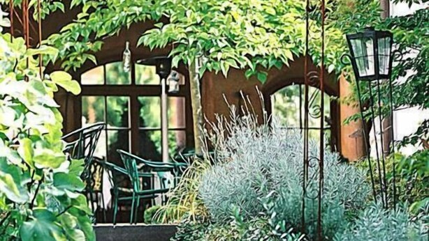 A set of stone steps leading to a wooden door, surrounded by lush greenery and potted plants. - Hotel Restaurant Adler (Lahr)