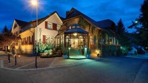 A hotel with a traditional architectural style, featuring a prominent entrance with a glass canopy and a well-lit facade. - Hotel Restaurant Adler (Lahr)