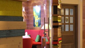 A hallway with a wooden staircase, a red sofa, and a glass door. - Hotel Restaurant Adler (Lahr)
