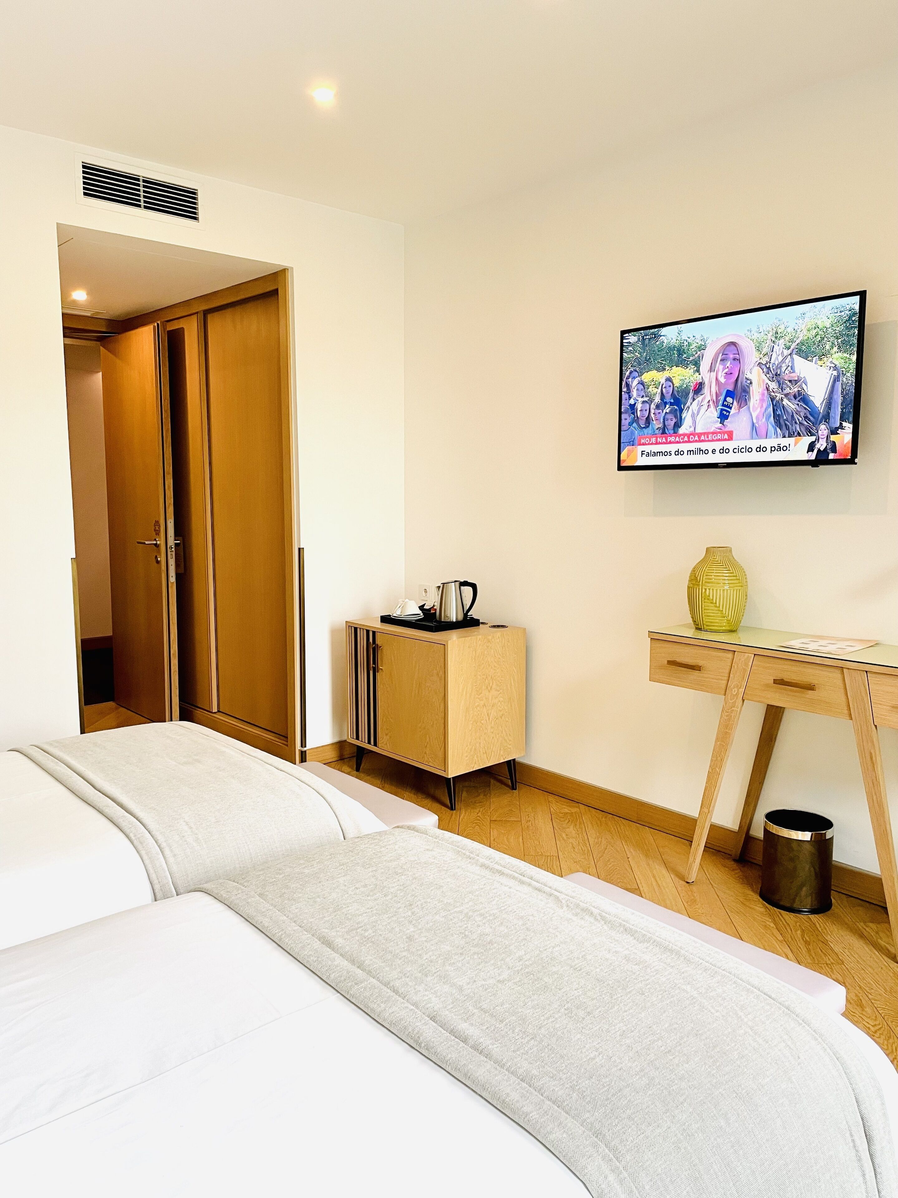 A hotel room with a bed, a desk, a TV, and a cabinet.
