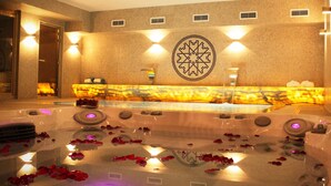 A spa area with a hot tub, rose petals, and a decorative wall with a geometric pattern. - Castelo Hotel (Chaves)
