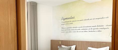 Una habitación de hotel con dos camas, cabeceros de madera, una pared con un cartel de texto y suelo de madera.