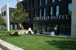 A modern hotel building with a sign reading "CASTELO HOTEL".