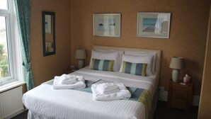 A hotel room with a large bed, two bedside tables, and two framed pictures on the wall. - The Kenbury (Shanklin)