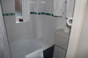 A bathroom with a bathtub, toilet, and a window. - The Kenbury (Shanklin)