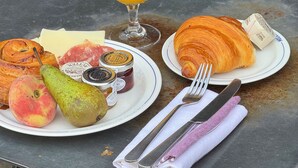 A table with a meal consisting of a croissant, fruit, cheese, and a glass of orange juice. - The Culpeper (London)