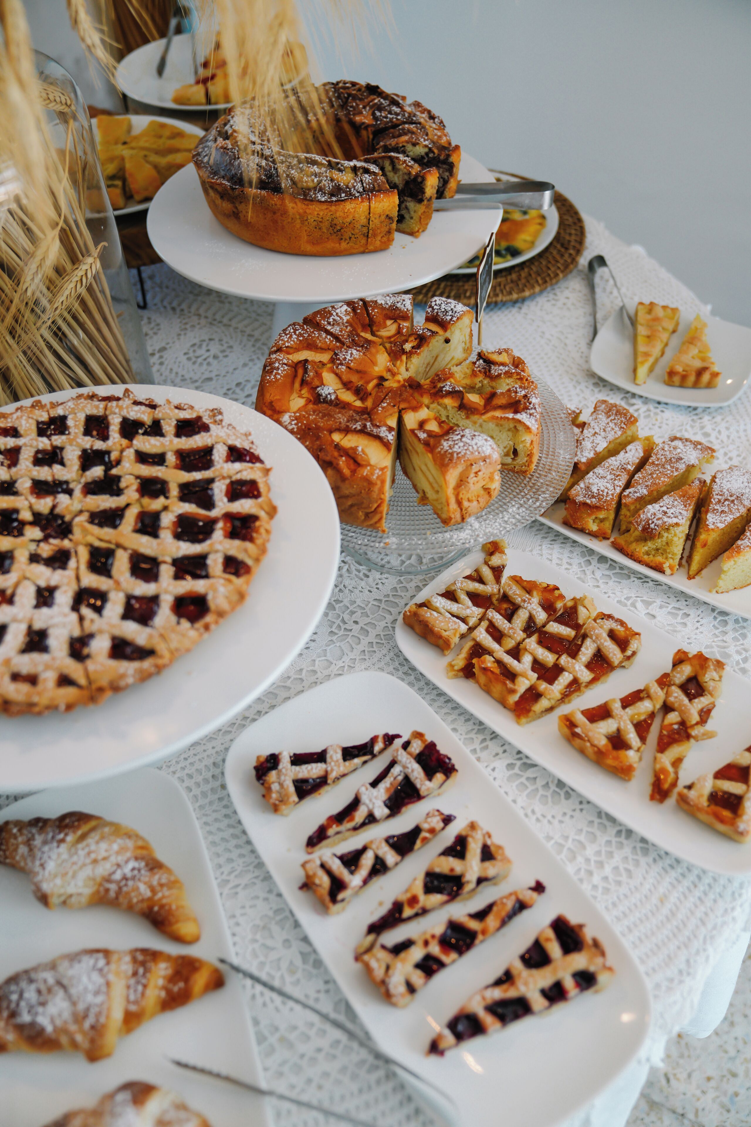 A table with various baked goods including pies, pastries, and a cake.