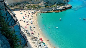 A coastal beach with a rocky shoreline, a castle on a cliff, and clear turquoise waters. - Il Borghetto Resort & Spa (Tropea)