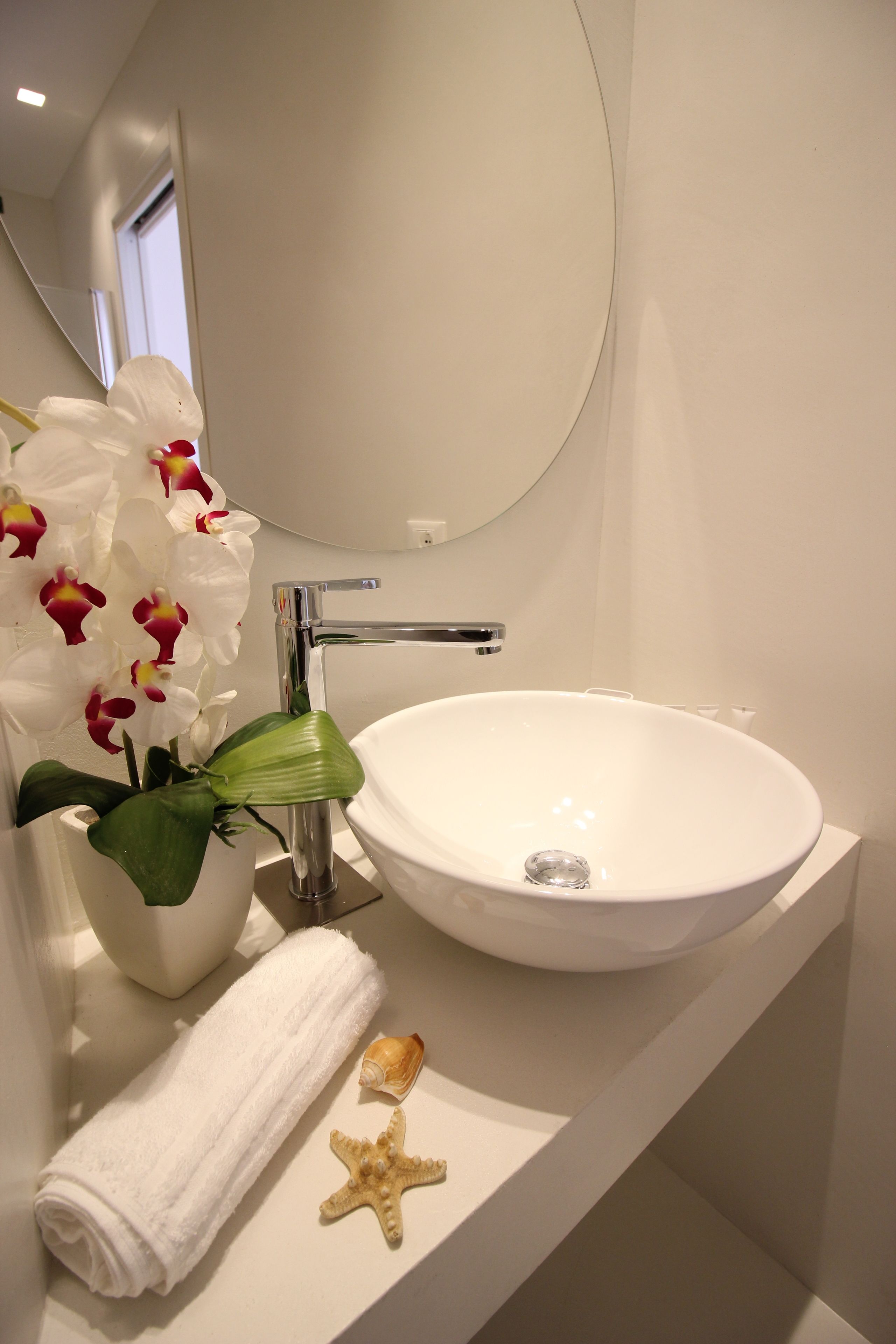 A bathroom with a white sink, a mirror, a towel, and a starfish decoration.