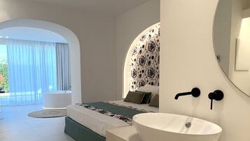 Een moderne slaapkamer met een groot bed, een witte wastafel en een spiegel.