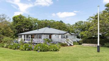 A two-story house with a porch, surrounded by a well-maintained lawn and flowering plants.