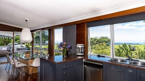 A modern kitchen with dark cabinetry, a granite countertop, and a view of the outdoors. - Rosewood Estate (Beechmont)
