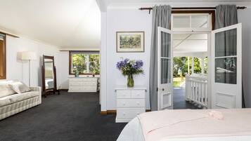 A bedroom with a bed, a dresser, a mirror, a vase with flowers, and a window with curtains.