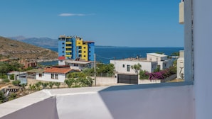 Un quartier résidentiel situé sur la côte, avec un immeuble à plusieurs étages, une vue sur la mer et un paysage vallonné en arrière-plan.