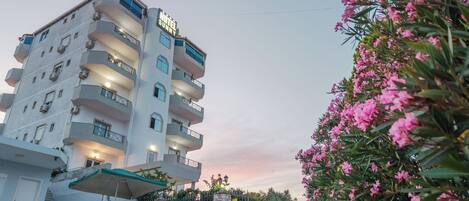 A multi-story hotel with balconies, a staircase, and a gated entrance.