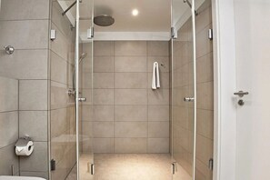 Eine moderne Dusche mit Glastüren, einer Handbrause und einem Handtuchhalter.