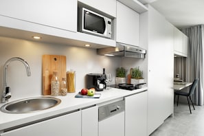 A modern kitchen with a built-in microwave, stainless steel sink, and a coffee maker. - BD Munich Olympiapark (Munich)