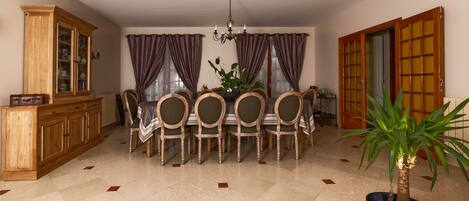 A dining area with a round table, chairs, a chandelier, and a cabinet.