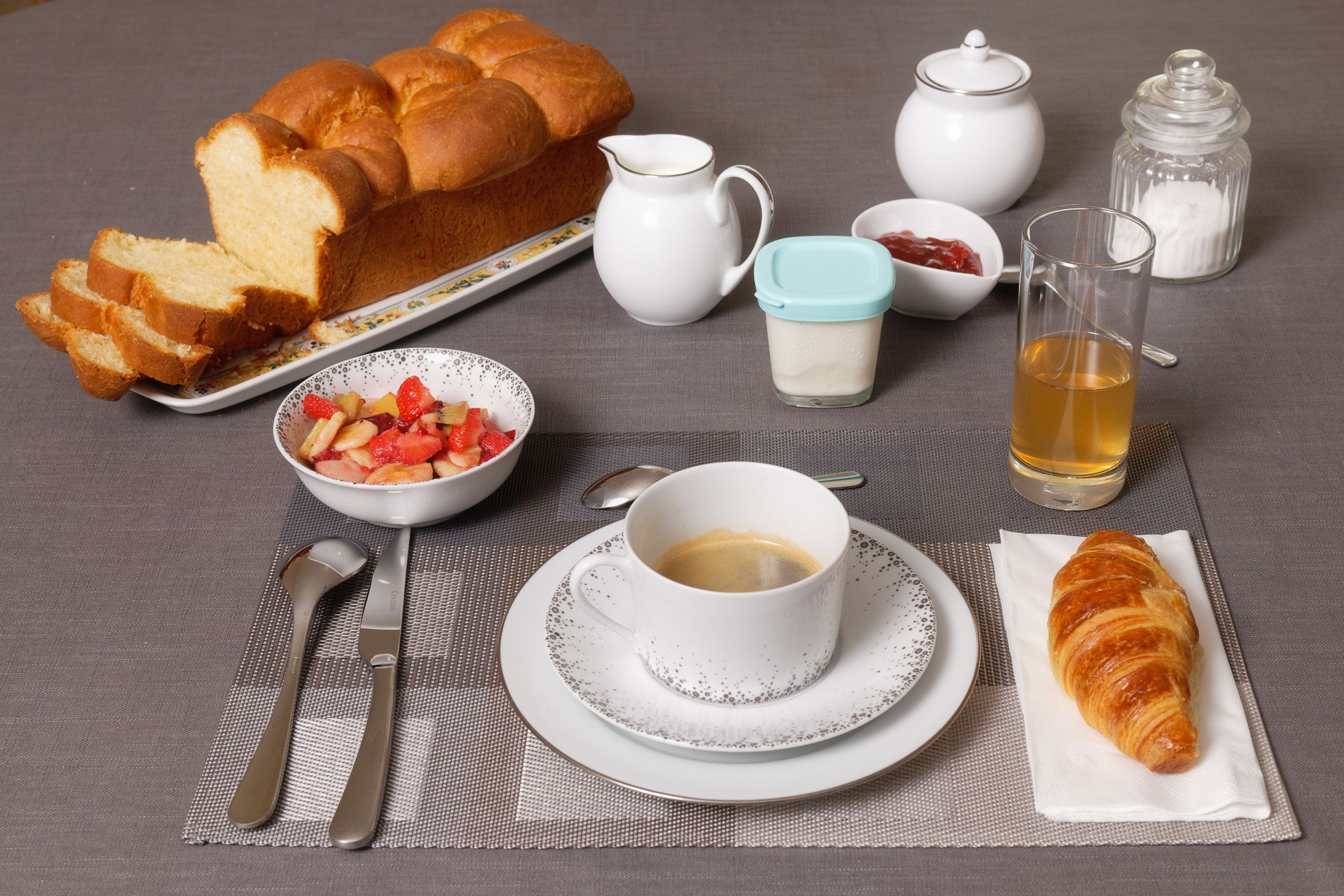 Desayuno con pan, fruta, café y un croissant.