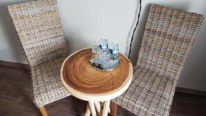 A wicker chair and table set in a room with a wooden floor. - Le Clos Magedon (Médan)