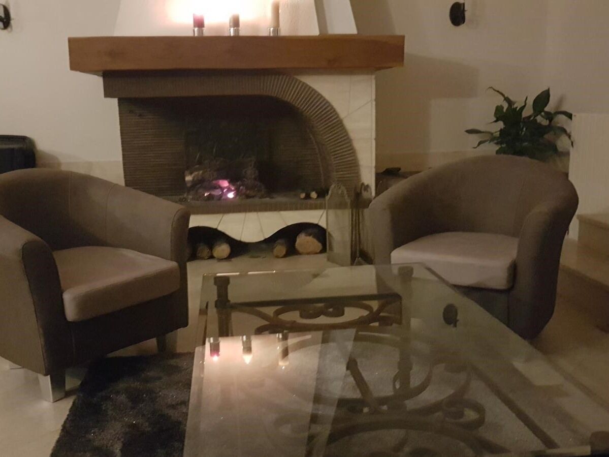 Un soggiorno con due poltrone, un tavolino in vetro e un camino con mensola.
