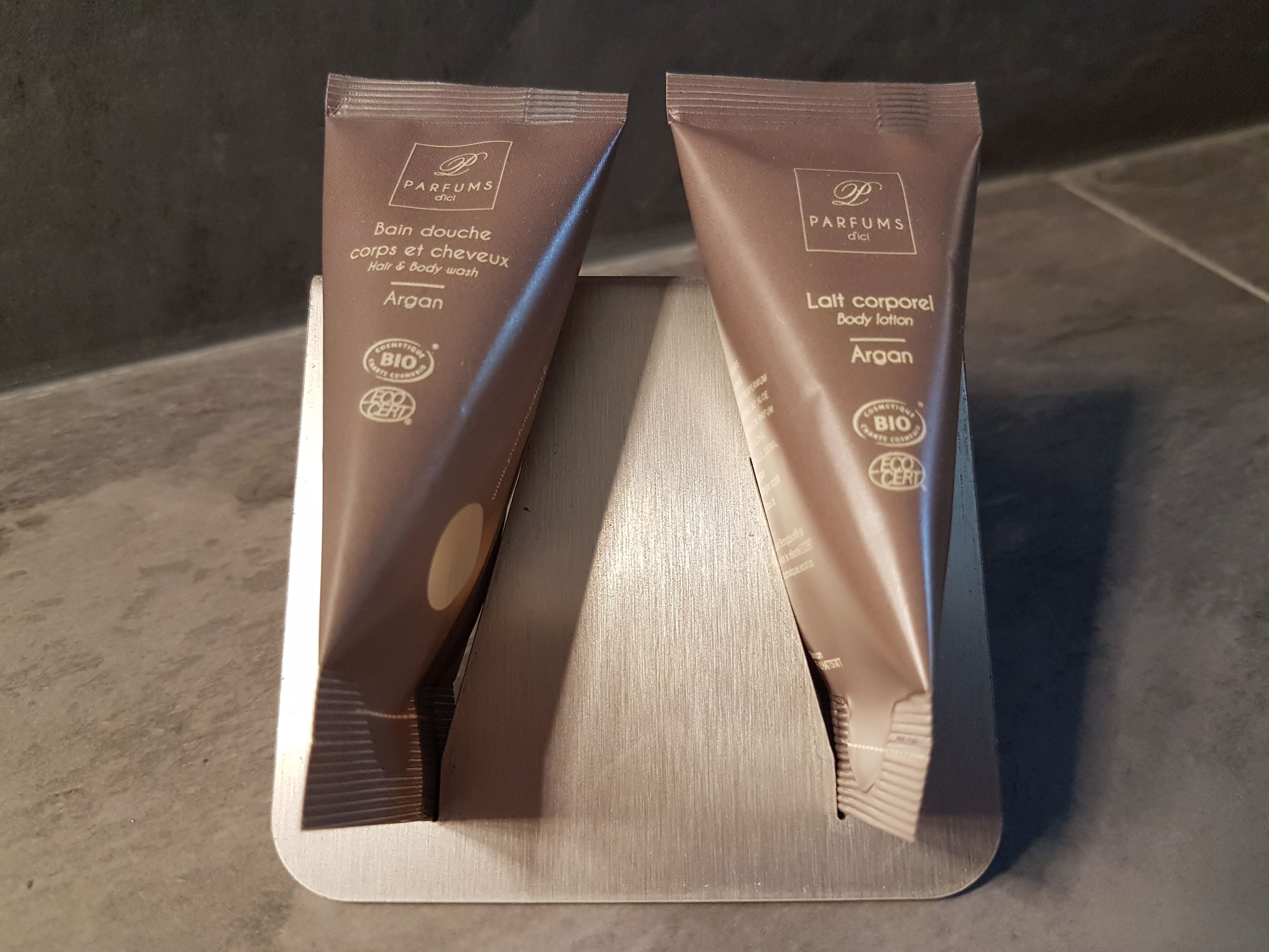 Two brown toiletry bags on a metallic stand.