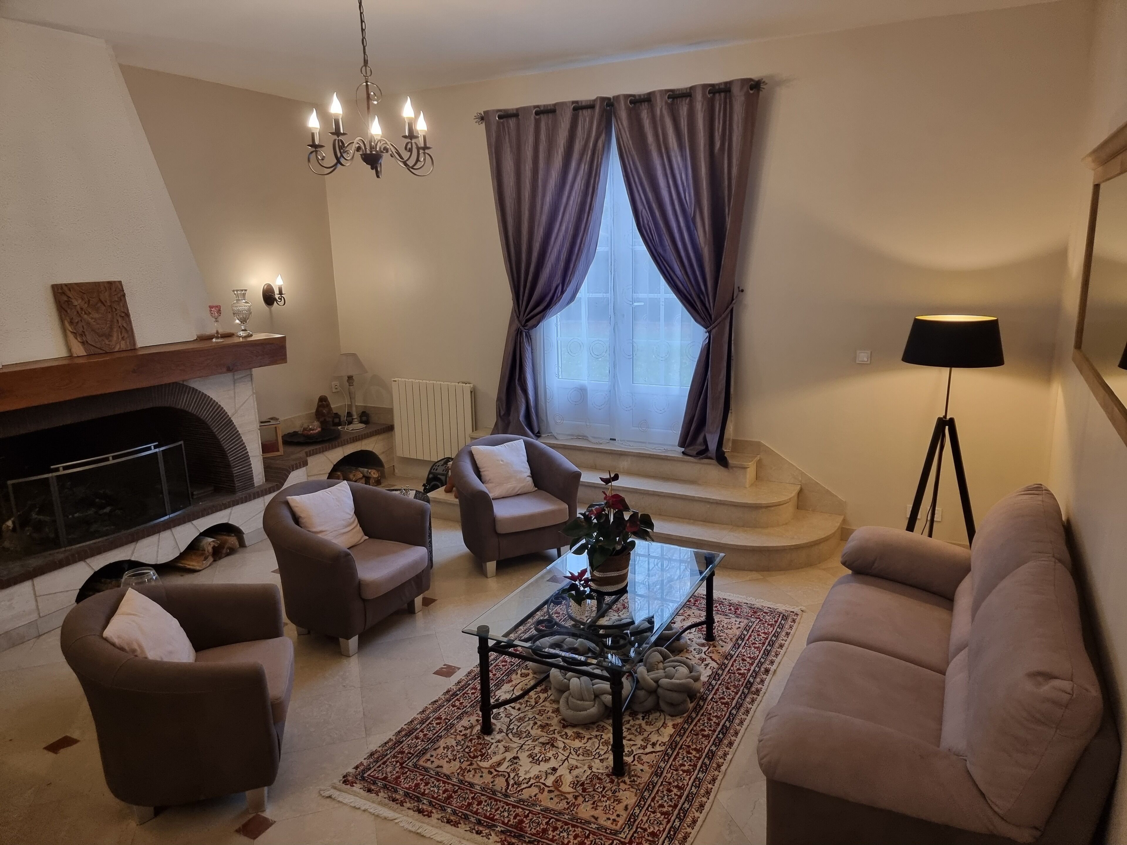 Een woonkamer met een open haard, twee fauteuils, een bank, een salontafel en een vloerlamp.