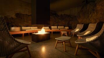 A lounge area with a fire feature, seating arrangements, and a stone wall backdrop.