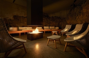 A lounge area with a fire feature, seating arrangements, and a stone wall backdrop.