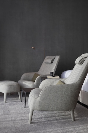 A modern room with a grey sofa, a matching ottoman, and a small table with a book and a cup.