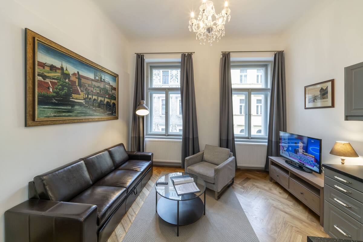 A modern living room with a sofa, armchair, coffee table, TV, and artwork.