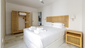 Une chambre d’hôtel avec un grand lit, un ventilateur de plafond, une armoire en bois et une table de chevet avec une lampe.