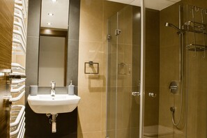 A modern bathroom with a glass-enclosed shower, a sink with a mirror, and a towel rack. - WS Sauna Apartments (Kraków)