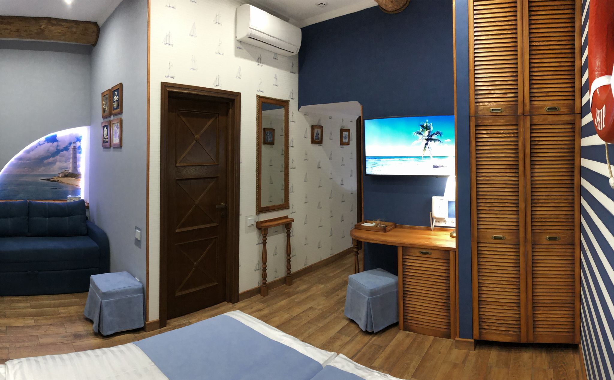 A room with a wooden door, a TV on the wall, a sofa, and a small table.