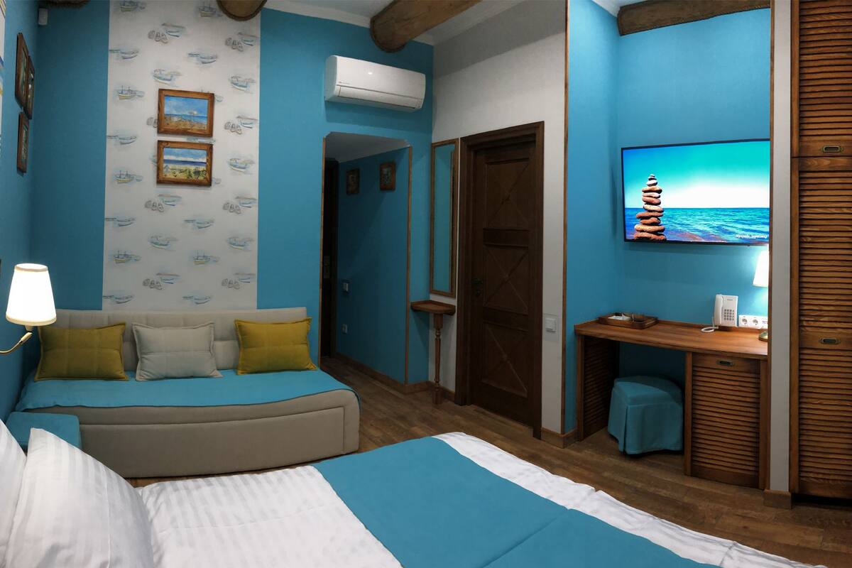 A bedroom with a bed, a desk, a chair, and a TV.