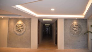 A hallway with a modern ceiling design, recessed lighting, and decorative wall carvings. - Thazin Palace A Hotel (Ngapali)