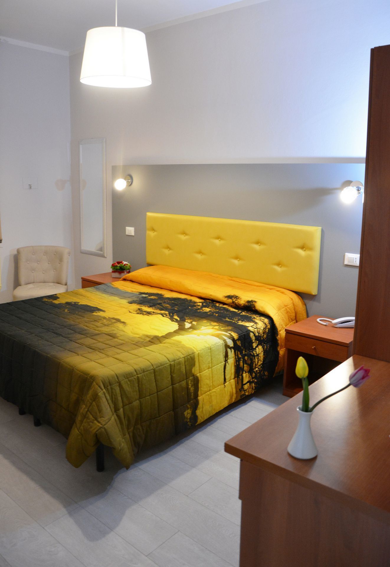 A bedroom with a bed, a chair, a bedside table, and a nightstand.
